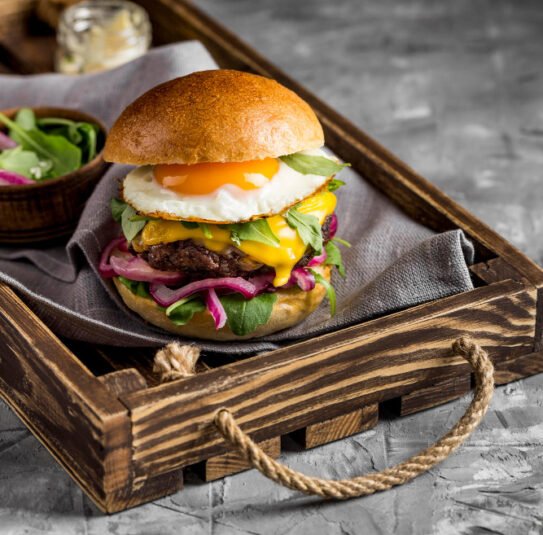 Burger with cheese and egg on wooden tray