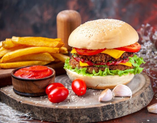 Delicious Hamburger wooden dish behind fries and ketchup