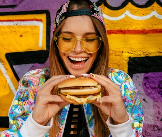 Woman is holding tasty burger by two hands